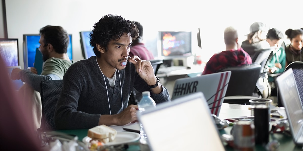 man in an office working on his computer amongst coworkers