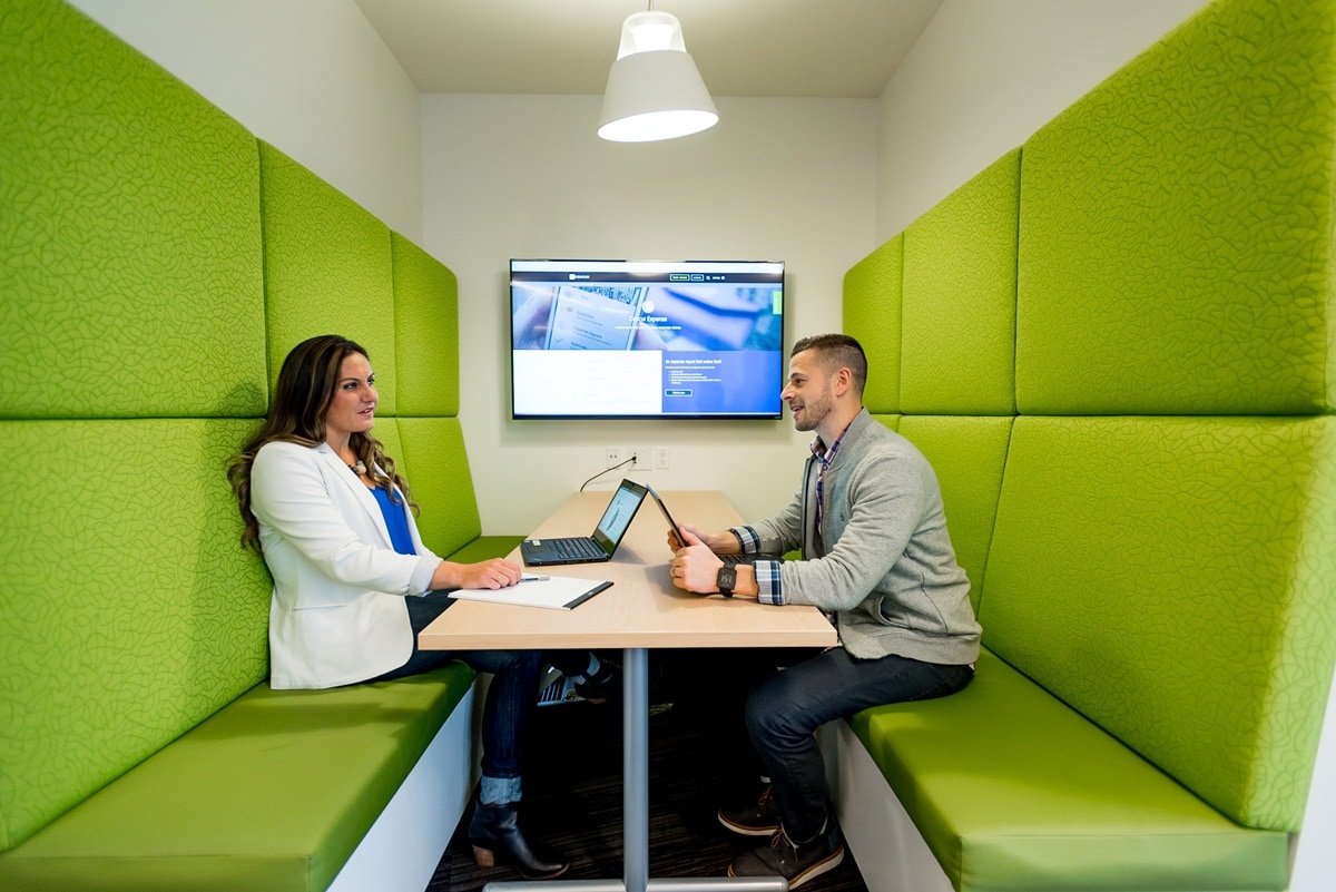 Two people sitting in work booth 