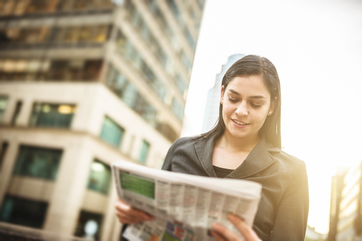 Lady standing in street reading paper