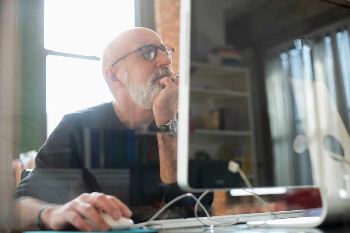 Man with beard and glasses looking a computer screen